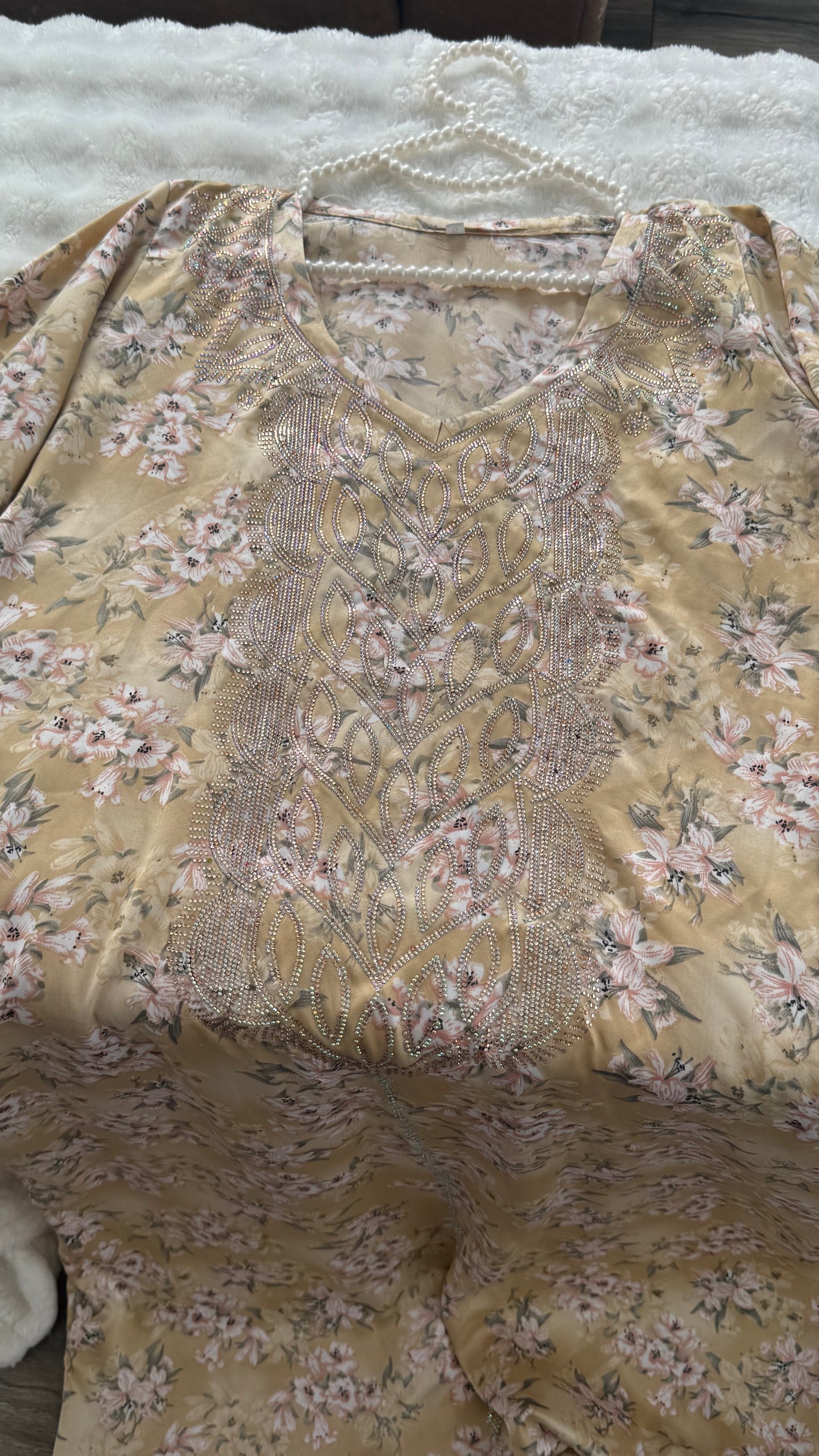 Floral patterned fabric with embroidery on a hanger against a textured surface.