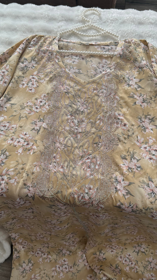 Floral patterned fabric with embroidery on a hanger against a textured surface.